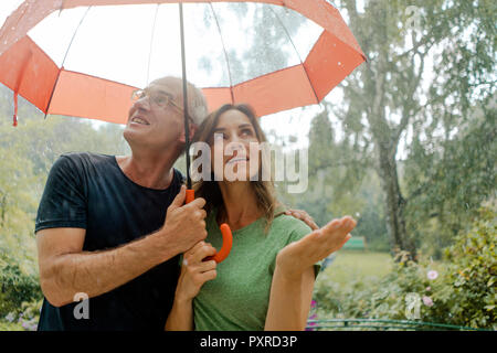 Lächelnd reifes Paar im Regen unter dem Dach Stockfoto