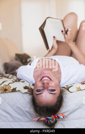Porträt der glückliche junge Frau im Bett zu Hause liegen mit Tagebuch Stockfoto