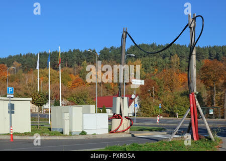 Das Kabel des Hochspannungs-electric power transmission Line auf Holzpfähle oberhalb der Straße festgelegt ist. Sonnigen Herbsttag städtisch-industriellen landsckape Stockfoto