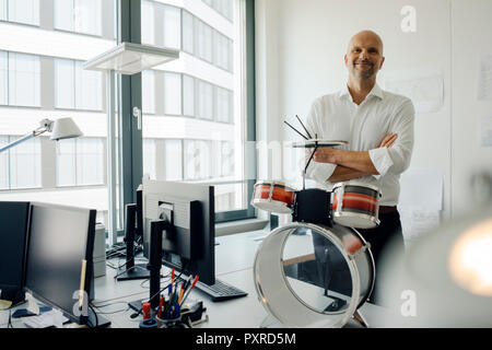 Unternehmer stehen in seinem Büro, plaing Drums Stockfoto