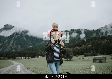 Österreich, Vorarlberg, Mellau, Mutter mit Kleinkind auf den Schultern auf einer Reise in die Berge Stockfoto