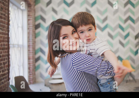 Abendessen mit der Familie. Familie empfängt Gäste, ein festliches Meeting. Junge Mama mit Sohn auf Händen Stockfoto