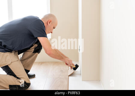 Männliche Arbeitnehmer, die Installation von neuen Holz- Laminat auf einem warmen Film Folie Erdgeschoss. Infrarot Fußbodenheizung unter Laminat Stockfoto