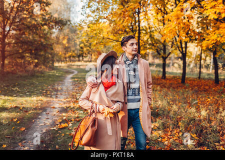 Junges Paar in Liebe Spaziergänge im Herbst Wald unter bunten Bäumen. Mann und Frau umarmen und sprechen bei Sonnenuntergang Stockfoto