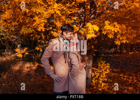 Junges Paar in Liebe Spaziergänge im Herbst Wald unter fallenden Blätter. Stilvolle Menschen umarmen und Chillen im Freien Stockfoto