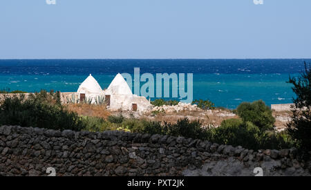 Monopoli, Italien. Zwei weiße traditionellen Trockenmauern Trulli in der Nähe des Meeres in der Nähe von Monopoli in Apulien gewaschen. Stockfoto