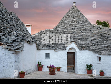 Trockenmauern, weiß getünchten, konische überdachte Trulli auf einer Straße in der Aia Piccola Bereich von Alberobello, Puglia, Italien. Am frühen Morgen fotografiert. Stockfoto