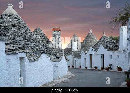 Trockenmauern, weiß getünchten, konische überdachte Trulli auf einer Straße in der Aia Piccola Bereich von Alberobello, Puglia, Italien. Am frühen Morgen fotografiert. Stockfoto