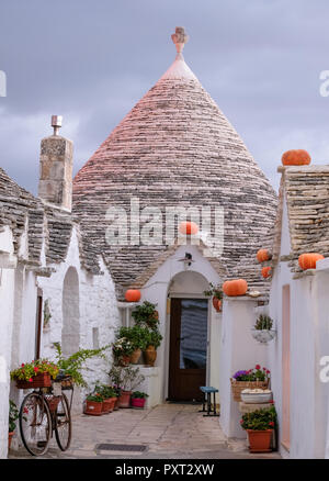 Trulli auf der Straße in Alberobello, Apulien. Kürbisse haben auf der Traufe platziert wurde Halloween zu feiern. Bei Sonnenaufgang fotografiert. Stockfoto