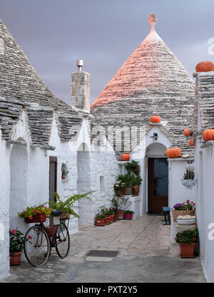 Trulli auf der Straße in Alberobello, Apulien. Kürbisse haben auf der Traufe platziert wurde Halloween zu feiern. Bei Sonnenaufgang fotografiert. Stockfoto