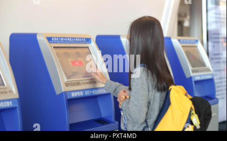 China Wuhan Tianhe - September 10, 2018: Die junge Frau mit dem Check-in-Automaten am Flughafen erhalten der Bordkarte. Es ist blur Bild. Stockfoto