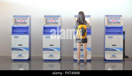 China Wuhan Tianhe - September 10, 2018: Die junge Frau mit dem Check-in-Automaten am Flughafen erhalten der Bordkarte. Es ist blur Bild. Stockfoto