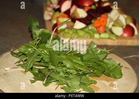 Löwenzahnblätter und gehackte Obst und Gemüse auf Holzplatten Stockfoto