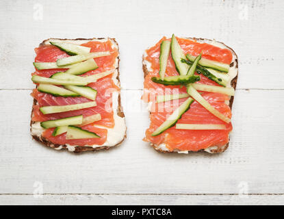 Zwei Sandwiches mit roten Fischen und Gurke auf Holz- Hintergrund Stockfoto