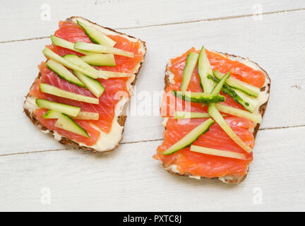 Zwei Sandwiches mit roten Fischen und Gurke auf Holz- Hintergrund Stockfoto