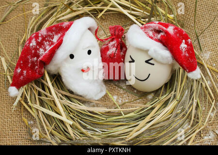 Glückliche Eier mit bemalten Gesichtern im Nest für Weihnachten Stockfoto