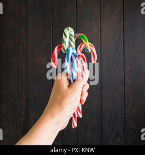 Weihnachten Bonbons in weibliche Hände auf dunklem Hintergrund mit Kopie Raum Stockfoto