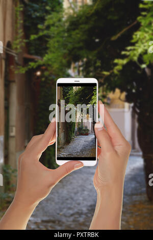Ein Tourist ist ein Foto von einem der Straßen im Viertel Trastevere in Rom, Italien, und auf einem Mobiltelefon Stockfoto