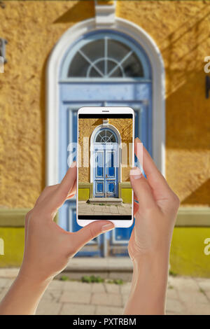 Ein Tourist ist ein Foto des alten schönen hölzernen Tür in der Altstadt von Tallinn, und auf einem Mobiltelefon Stockfoto