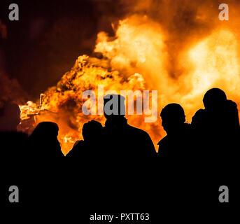 Eine Zusammenkunft von Menschen gegen einen brennenden Lagerfeuer auf November ab dem 5. Stockfoto