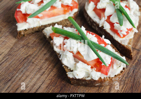 Scheiben Roggenbrot mit Sire Feta, Tomaten und Zwiebeln auf einem Holzbrett. Selektive konzentrieren. Stockfoto