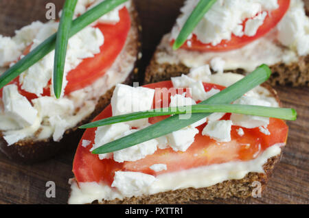 Scheiben Roggenbrot mit Sire Feta, Tomaten und Zwiebeln auf einem Holzbrett. Selektive konzentrieren. Stockfoto