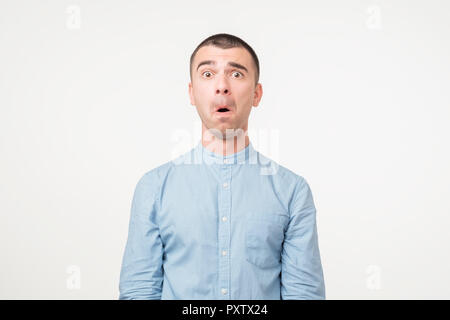 Portrait von ängstlichen jungen Mann im blauen Hemd halten Mund weit offen, Stress Stockfoto