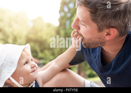 Kleines Mädchen Fütterung Vater mit einer Traube Stockfoto