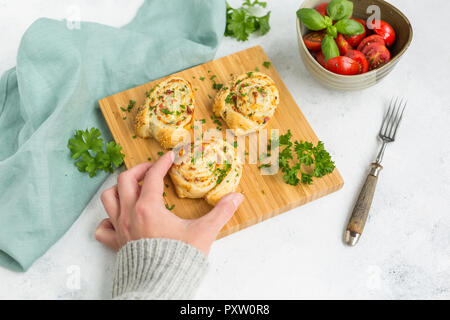 Woman's Hand, klebrigen Brötchen mit Feta, Käse, Speck und Petersilie Stockfoto