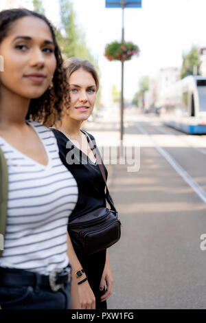 Zwei junge Frauen überschreiten Straße in der Stadt Stockfoto