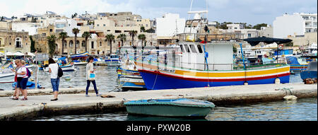 Touristen und Fischerboote im Hafen von Marsaxlokk, Malta - Panorama Stockfoto