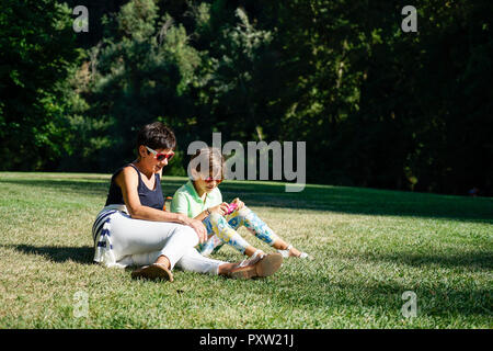 Mutter und Tochter Fotografieren, sitzen auf Gras Stockfoto