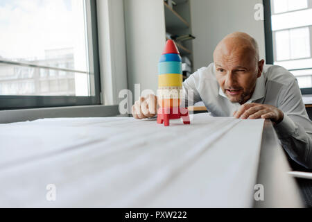 Geschäftsmann spielen mit Spielzeug, Rakete im Büro Stockfoto