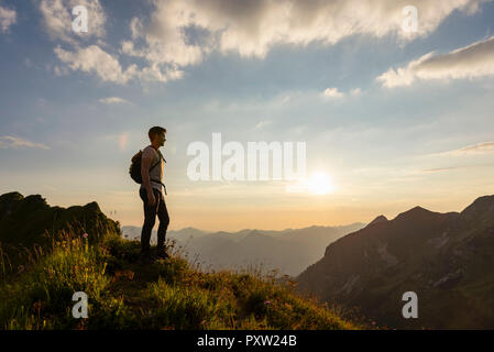 Deutschland, Bayern, Oberstdorf, Mann auf einer Wanderung in den Bergen mit Blick auf Sonnenuntergang Stockfoto