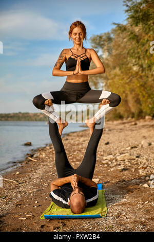 Junger Mann und Frau praktizieren Acro Yoga Stockfoto