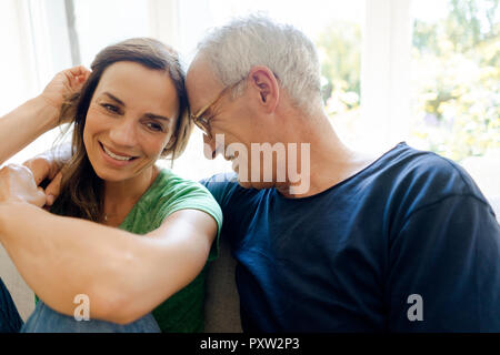 Glückliches junges Paar auf der Couch zu Hause sitzen Stockfoto