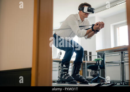 Geschäftsmann Skifahren im Büro, mit VR-Brille Stockfoto