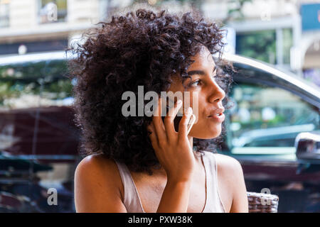 Deutschland, Frankfurt, Porträt der jungen Frau mit Curly am Telefon Stockfoto