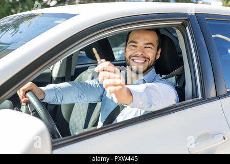 Closeup Porträt, junge heiter, fröhlich, lächelnd, Männer halten sich Schlüssel für Ihr erstes neues Auto Stockfoto