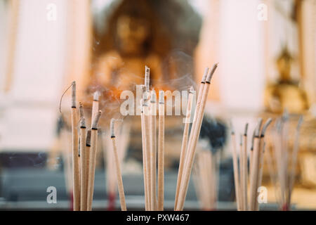 Thailand, Bangkok, Rauchopfer vor Buddha Statuen in einem buddhistischen Tempel Stockfoto