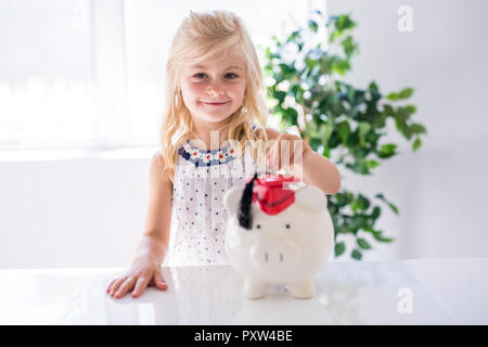 Ein lächelndes Mädchen mit piggy Bank und Geld zu Hause Stockfoto