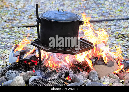 Ein schwarzer Topf auf einem Grill über ein großes Feuer Stockfoto