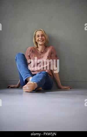 Portrait von lächelnden reife Frau zu Hause sitzen auf dem Boden Stockfoto