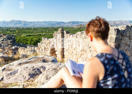 Griechenland, Peloponnes Argolis, Tiryns, archäologische Stätte, weiblichen Touristische lesen Reiseführer Stockfoto