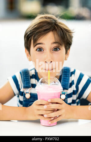 Portrait von kleinen Mädchen trinken Erdbeer milchshake an Cafe Stockfoto