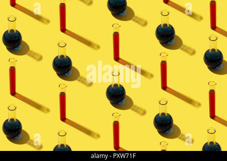 Reihe von Röhrchen mit Flüssigkeit, gelber Hintergrund Stockfoto