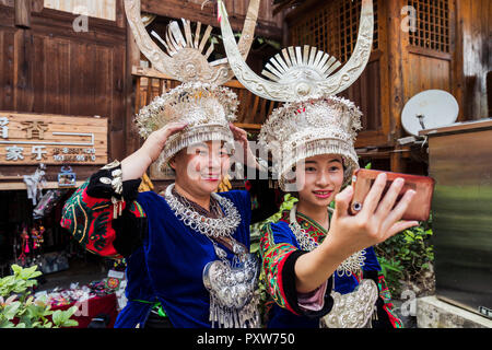 China, Yunnan, zwei Miao Frauen in traditionellen Gewändern und Kopfbedeckungen eine selfie mit Smartphone Stockfoto