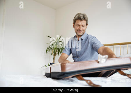 Reife Männer packen Koffer im Schlafzimmer Stockfoto