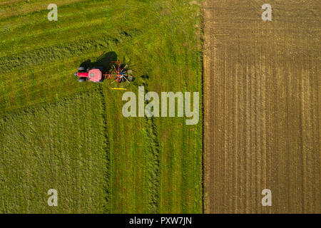 Luftbild von Oben nach Unten ein Roter Traktor Ackerland Anbau mit einem sich drehenden Rotorblatt in ländlichen Slowenien Stockfoto