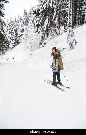 Portrait von glücklichen jungen Frau Skifahren im Winter Wald Stockfoto